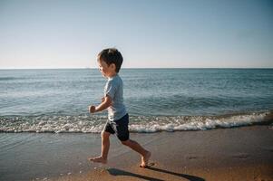 linda pequeño chico corriendo en playa y tener divertido foto