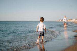 linda pequeño chico corriendo en playa y tener divertida. foto
