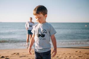 Mother and son playing on the beach at the sunset time. Concept of friendly family photo