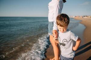 Mother and son playing on the beach at the sunset time. Concept of friendly family photo