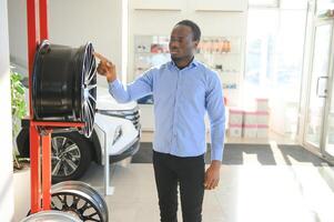 An African man buys car rims in an auto parts store photo