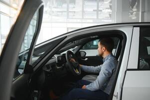 un joven hombre elige un nuevo coche a un coche concesión. foto