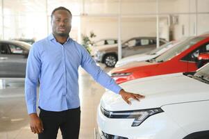 hermoso africano hombre elegir un nuevo coche a el concesión foto