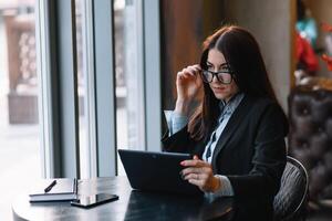 Happy young businesswoman using tablet computer in a cafe. Selective focus photo