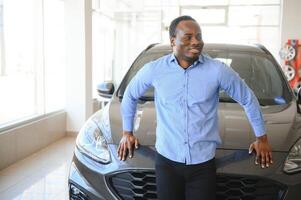 Handsome African man choosing a new car at the dealership photo