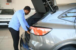 Handsome African man choosing a new car at the dealership photo