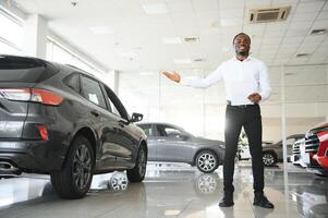 carros concesión concepto. auto vendedor afro hombre en pie en automóvil centrar foto