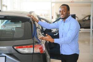 hermoso hombre es en pie cerca su nuevo coche y sonriente foto