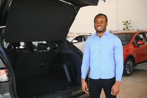 hermoso hombre es en pie cerca su nuevo coche y sonriente foto