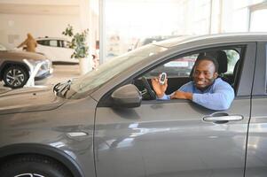 alegre negro hombre sentado en lujo automóvil, prueba conducir, transporte foto