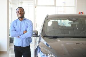 hermoso hombre es en pie cerca su nuevo coche y sonriente foto