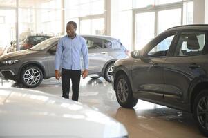 hermoso africano hombre elegir un nuevo coche a el concesión foto