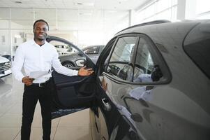 retrato de hermoso africano americano vendedor a lugar de trabajo en coche sala de exposición foto