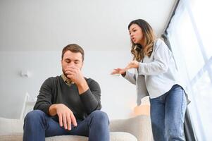 Family quarrel, man and woman sitting on sofa at home. angry woman yells at her husband photo