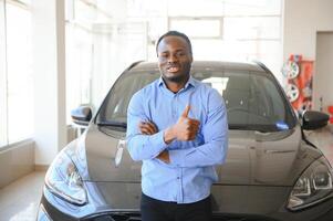 Handsome man is standing near his new car and smiling photo