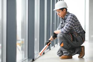 Workman in overalls installing or adjusting plastic windows photo