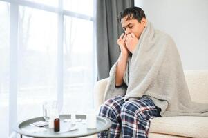 A sick Indian is treated at home and uses a nasal spray. Healthcare concept photo