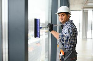 Male janitor cleaning window in office photo