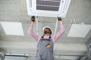 african Male Technician Repairing Air Conditioner. photo