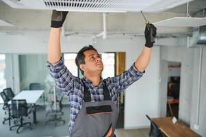 retrato de joven masculino indio técnico reparando aire acondicionador. aire acondicionador refacción. foto