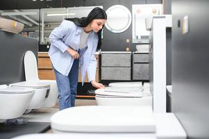 Young woman choosing bathroom toilet bowl and utensils for his home photo