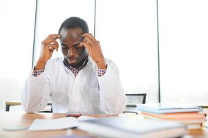 Tired african male therapist sitting in his office photo