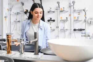 Woman inspects and chooses new kitchen or bath tap faucet at a hardware store photo