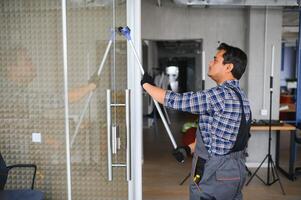 masculino profesional limpieza Servicio trabajador limpia el ventanas y tienda ventanas de un Tienda con especial equipo foto