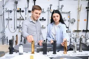Couple choosing new sink faucet for their home in modern appliances store photo