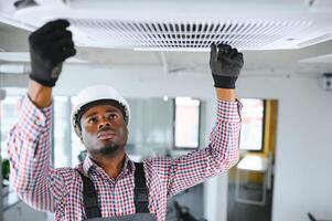 Happy african Male Technician Repairing Air Conditioner. photo