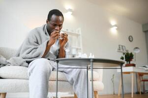 un africano hombre enfermo con crup o un frío es cubierto con un cobija a hogar foto