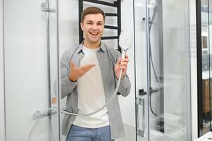 man choosing shower cabin and utensils for his home bathroom photo