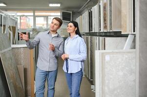 Couple looking ceramic and tiles for their new home floor. They are choosing in furnitures store photo