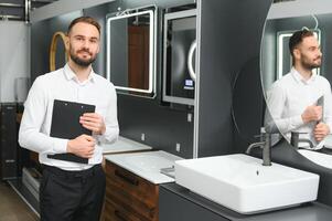 Happy salesman plumber man with paper tablet on plumbing shop photo