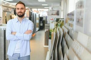 Young man choosing tiles at building market photo