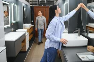 Positive couple choosing wash basin in bathroom furniture shop photo