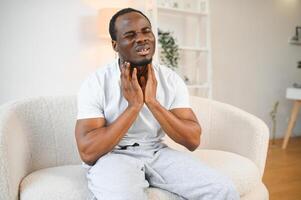 Sad black guy suffering from sore throat, touching highlighted neck, copy space photo