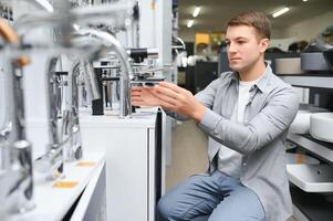 man chooses a bathroom faucet in a construction supermarket, plumbing repairs in the house photo