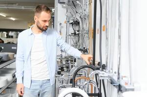 A large selection of water faucets. Man chooses a products in a sanitary ware store photo