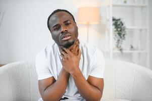 Sad black guy suffering from sore throat, touching highlighted neck, copy space photo