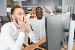 Two confident businessmen, financial analysts or investment advisers sitting at office desk photo