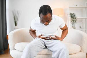 Black Man Having Stomachache Suffering From Painful Abdominal Spasm Standing Touching Aching Abdomen At Home photo