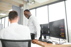 Two confident businessmen, financial analysts or investment advisers sitting at office desk photo