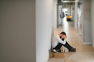 Sad fired businessman sitting outside meeting room after being dismissed photo