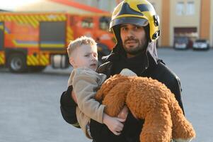 Firefighter holding child boy to save him in fire and smoke,Firemen rescue the boys from fire photo