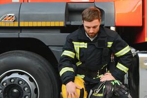 depressed and tired firefighter near fire truck photo