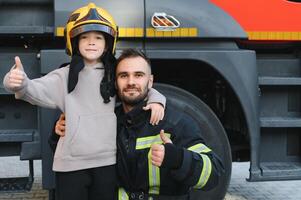 A firefighter take a little child boy to save him. Fire engine car on background photo