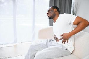 Black Man Having Stomachache Suffering From Painful Abdominal Spasm Standing Touching Aching Abdomen At Home photo