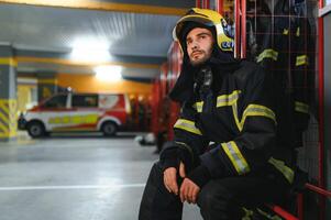 Fireman wearing protective uniform standing in fire department at fire station photo