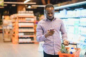 African man shopping at supermarket. Handsome guy holding shopping basket photo